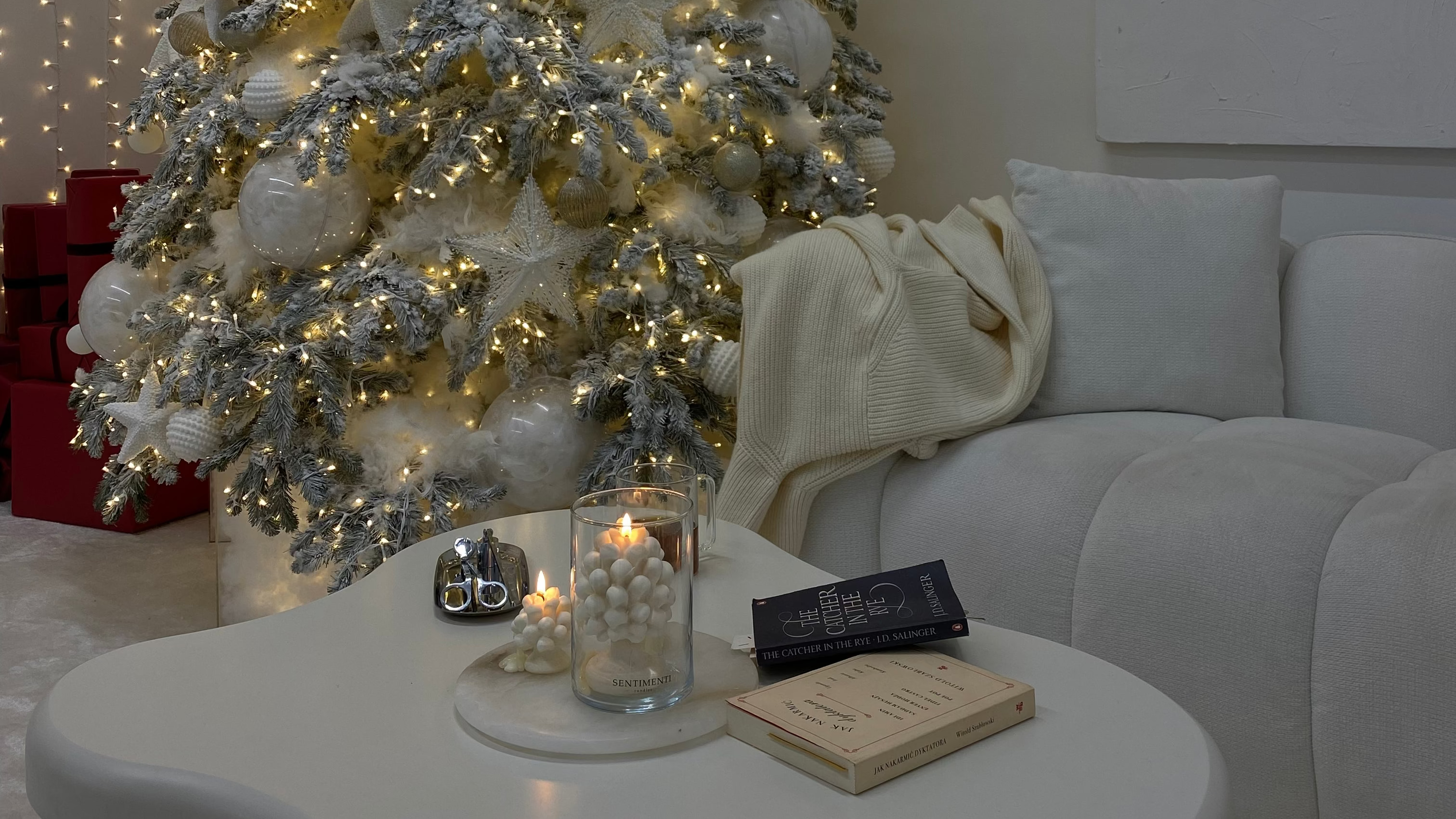Decorated Christmas tree in a living room with a white couch and table. candela decorativa natale regalo